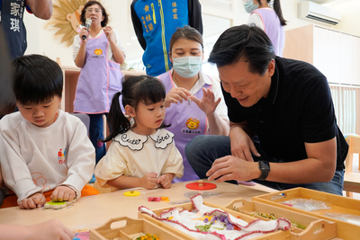 淡海國小公托啟用，新北市政府副市長朱惕之(右一)開心與孩子互動。