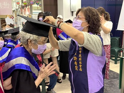 新北社會局副局長許秀能(右)為長輩們撥穗，88歲的阿任阿嬤(左)第一次參加「結訓典禮」感到很開心。