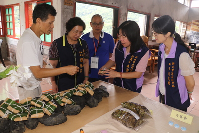 平溪電子天燈館長詹林欽（左） 為吳淑芳副局長說明礦光入坑前便當外 會另帶用野薑花包著的飯糰