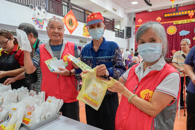賴恩典奶奶(右1)協助長輩領餐，在一旁的范發展爺爺(左1)看見攝影鏡頭，馬上提醒長輩們擺好Pose