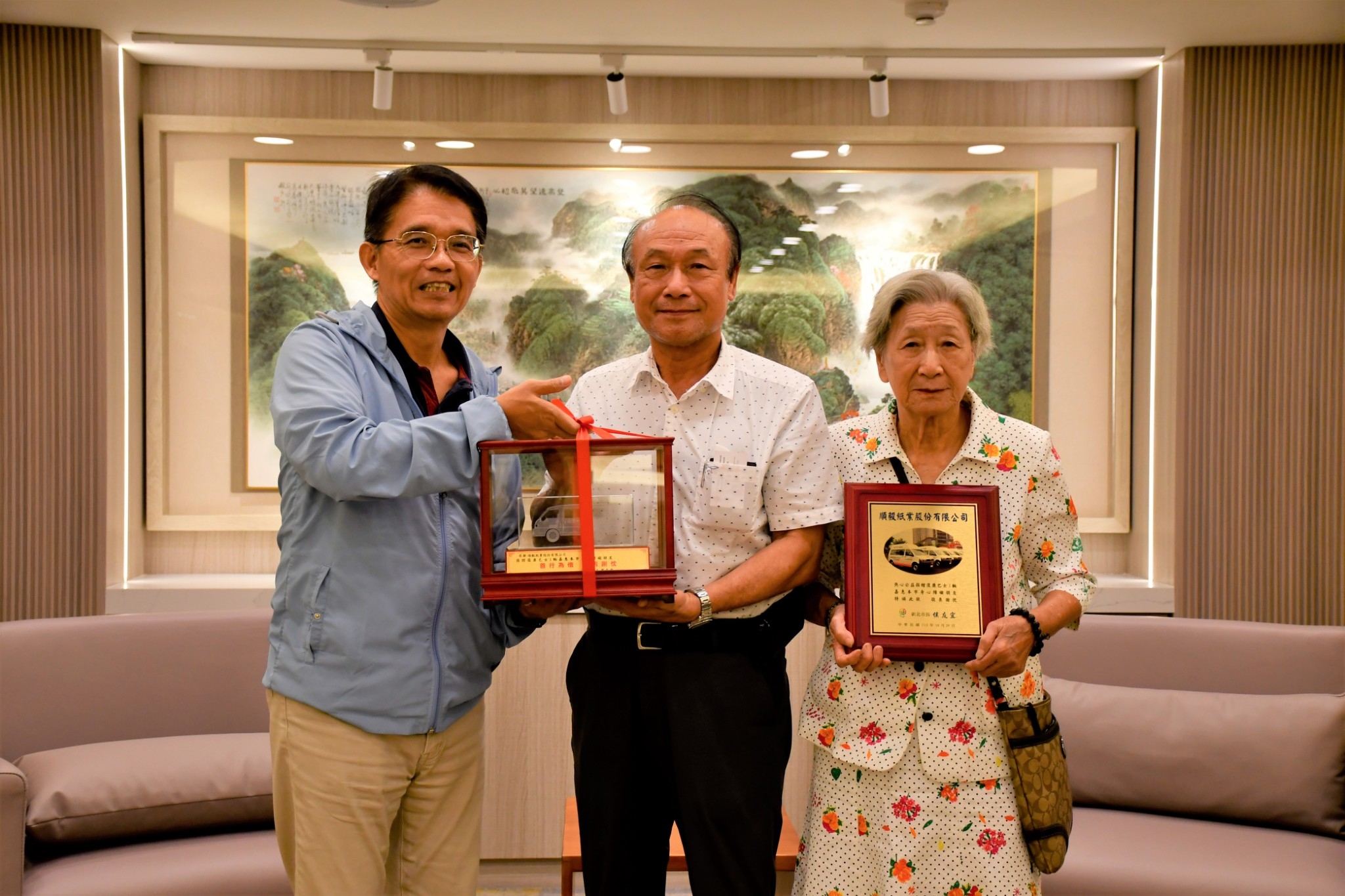  邱敬斌回贈復康巴士模型車及感謝牌給陳進步董事長及母親