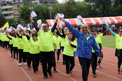 長青運動會運動員大進場，長輩們笑容滿面、精神抖擻地揮手繞場