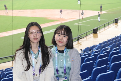  淡江大學西班牙語文學系畢業的朱采綸（左）與銘傳大學新聞與大眾傳播學系三年級的巫騏安在新莊棒球場擔任語言志工 獲得參賽的國際友人肯定