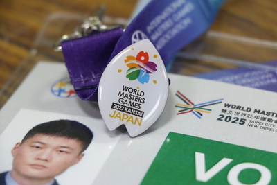 個人志工杜忠憲獲得日本射箭選手阿雅（AYA） 教練2027年下屆日本關西世壯運的徽章 他非常地珍惜 特地別在志工證上