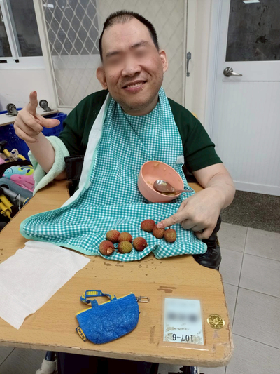 愛維養護中心住民穿上圍兜兜,開心地吃完飯,準備吃荔枝水果。