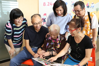 95歲的黃顧月娥（中坐者）看到媳婦葉翠媚（右前坐者）為她做的生命繪本  非常的開心