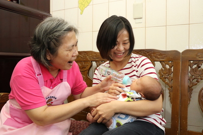 月嫂林碧桂（左）開心的指導餵奶姿勢  讓有點生疏的玉玄媽媽更有信心