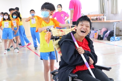 八里愛心教養院生小純(右1 )在同學協助下完成輪椅曲棍球進球相當開心