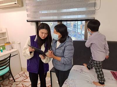 泰五林社福中心主責社工陳語彤引導越籍阿嬤在捐贈的善款上簽名,右為3歲女童。